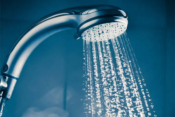 Showerhead releasing streams of water droplets against a blue background.
