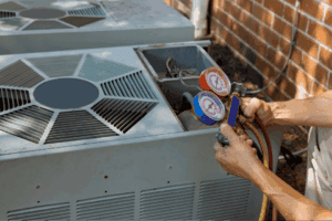 A person uses HVAC manifold gauges to check or service an outdoor air conditioning unit next to a brick wall, showcasing the precision and expertise required for quality heating services in Norwalk, CT.